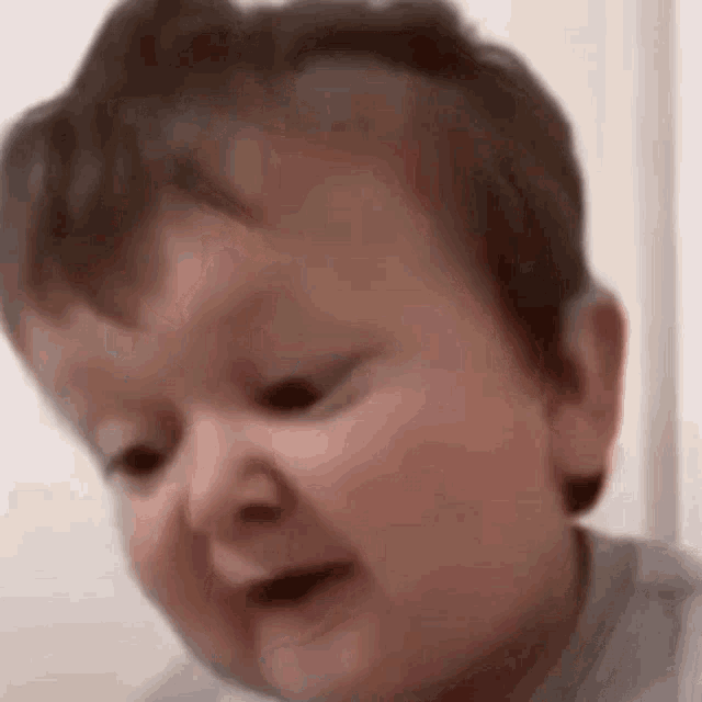 a baby is making a funny face and looking at the camera .