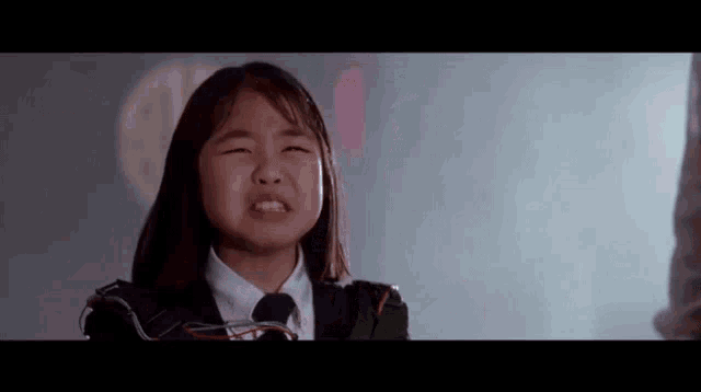 a young girl in a suit and tie is crying .