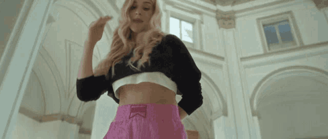 a woman wearing a black crop top and pink shorts with the word victoria on the waistband