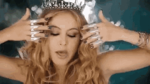 a woman wearing a crown and a lot of rings on her fingers .