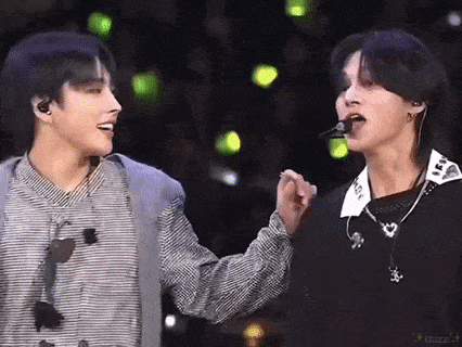 a couple of men are standing next to each other on a stage and one of them is holding the other 's hand .
