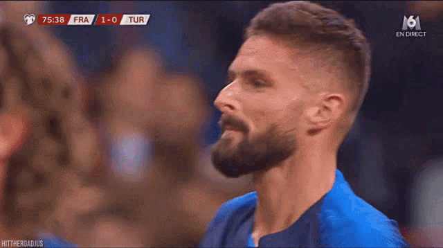 a man with a beard is standing in front of a screen that says ' en direct ' on it