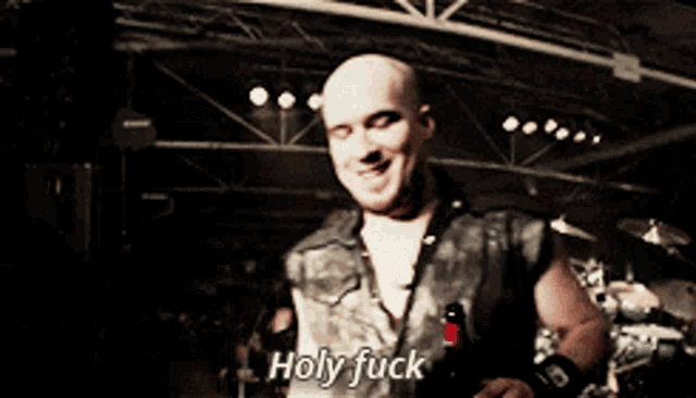 a man in a leather vest says holy fuck in a dark room