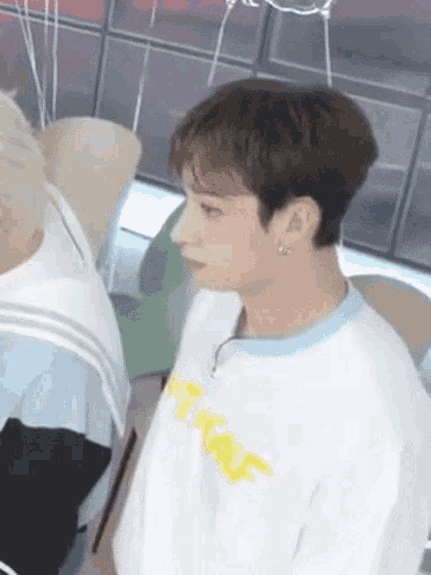 a close up of a young man wearing a white t-shirt with a yellow sticker on it .