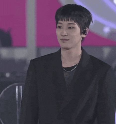 a young man wearing a black jacket and headphones looks at the camera