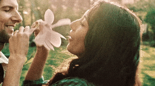 a man and a woman are holding a flower in their hands