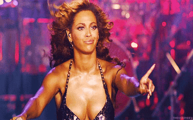 a woman in a very plunging top is pointing at something .