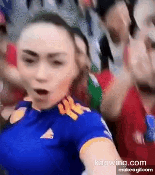 a woman in a blue adidas shirt is standing in a crowd of people .