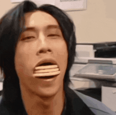 a man with a stack of cookies in his mouth is making a funny face .