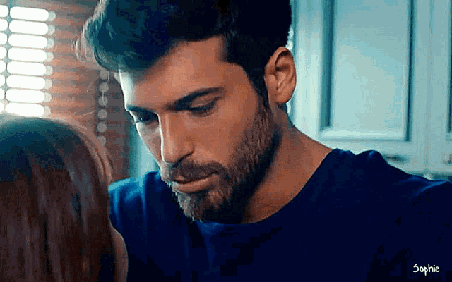 a man with a beard and a blue shirt is looking at a woman