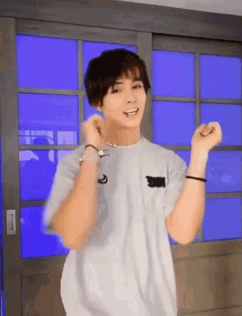 a young man in a white shirt is dancing in front of a blue wall .