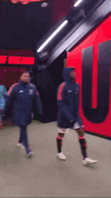 a group of soccer players are walking down a hallway in front of a sign that says " theatre of dreams "