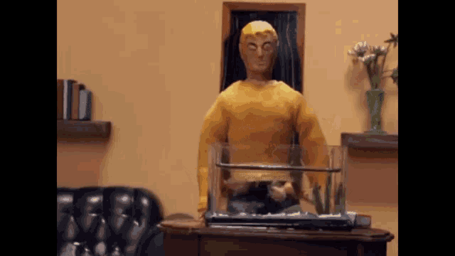a man in a yellow shirt is standing next to a fish tank