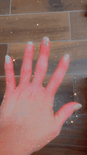 a person 's hand is holding a piece of watermelon on a tile floor