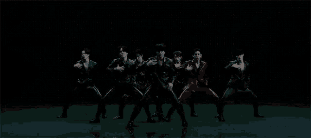 a group of young men are standing next to each other in a dark room and dancing .