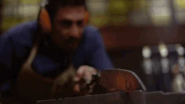 a man wearing headphones is working on a piece of wood