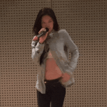 a woman is singing into a microphone with her shirt off