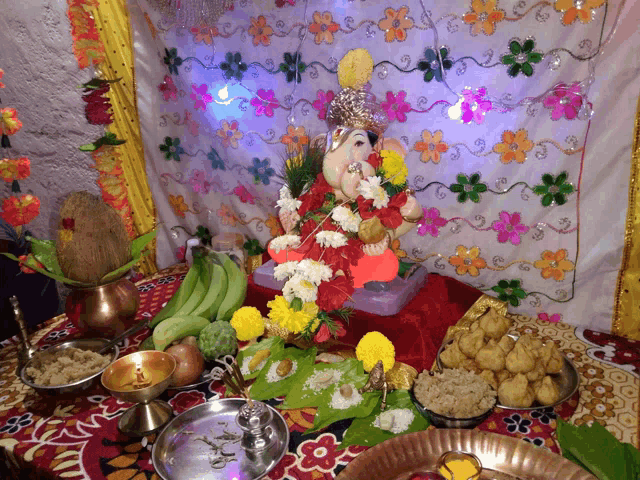 a table with plates of food and a statue of a deity on it