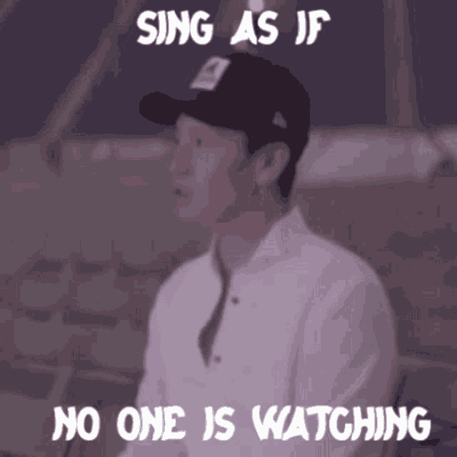 a man wearing a baseball cap with the words sing as if no one is watching above him