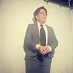 a man in a suit and tie is standing in front of a wall