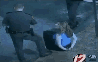 a woman in a blue shirt is being arrested by a police officer .