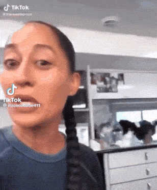 a woman in a blue shirt is making a funny face while standing in a kitchen .