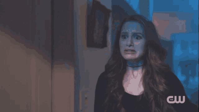a woman is screaming in a dark room with her mouth wide open .