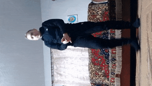a man in a black jacket is standing in front of a colorful rug