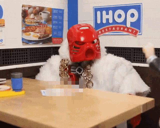 a man in a robot costume sits at a table in front of an ihop restaurant sign