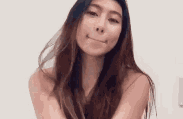a naked woman with long hair is smiling and making a face .