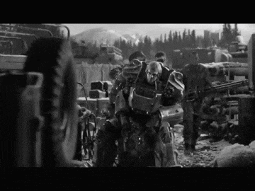 a black and white photo of a group of soldiers with a robot in the middle
