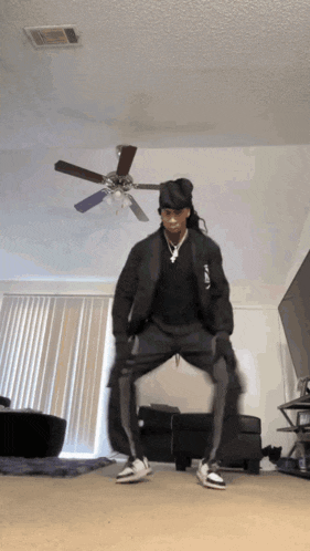 a person is dancing in a living room with a ceiling fan