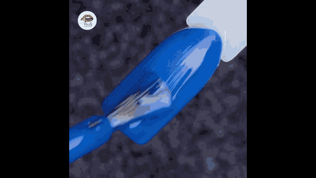 a close up of a blue nail with a white brush