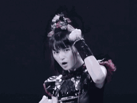 a girl in a metal outfit is dancing on a stage in a dark room .
