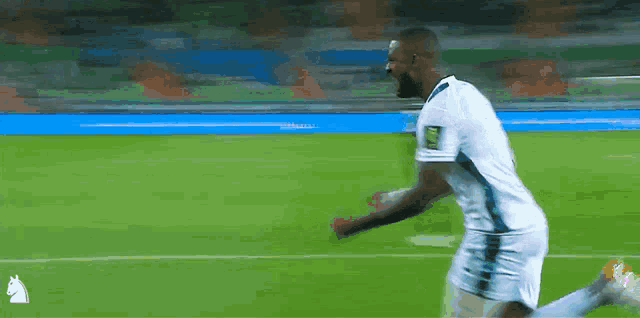 a soccer player is running on a field with a horse logo in the background