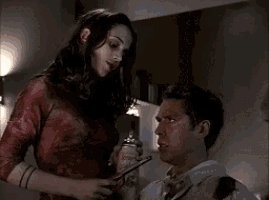 a woman is lighting a man 's face with a match