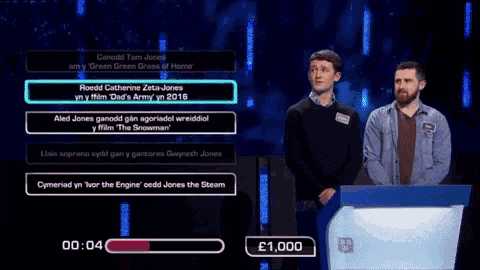 two men are standing next to each other on a stage talking to each other .