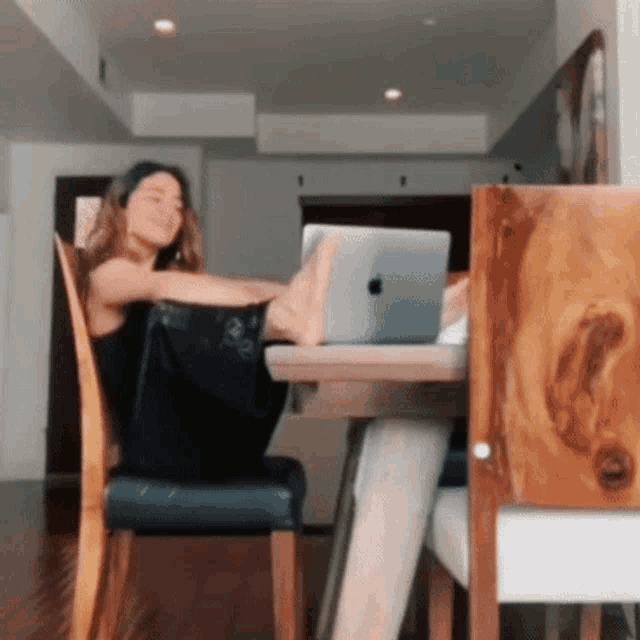 a woman sits in a chair with her feet up on a table with an apple laptop