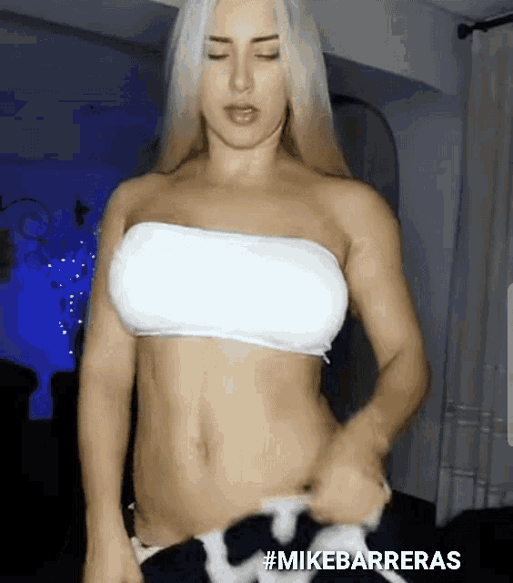 a woman in a white bra is standing in a room with her eyes closed .