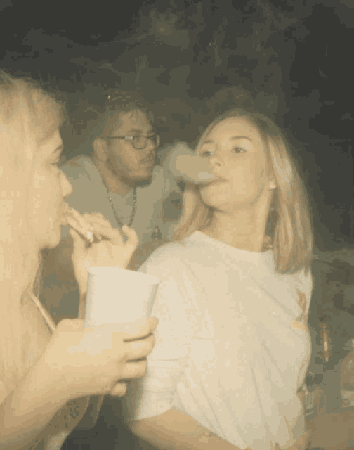 a woman smoking a cigarette while a man drinks beer