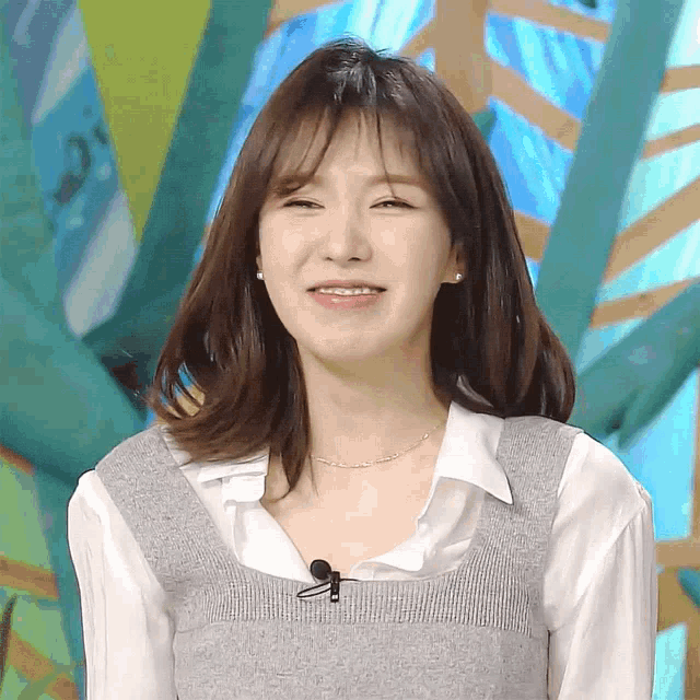 a woman wearing a sweater vest and a white shirt smiles for the camera