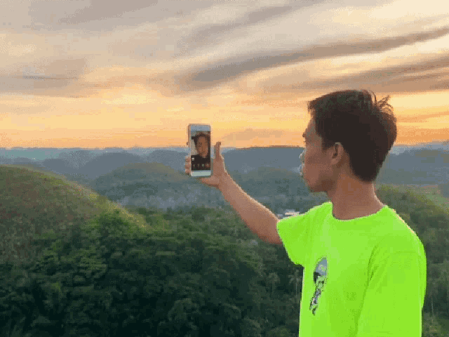 a man in a neon green shirt is taking a picture of himself with his phone