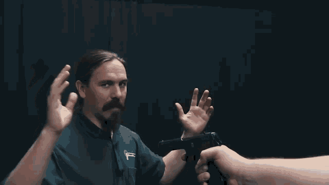 a man with a beard is holding a gun in his hand