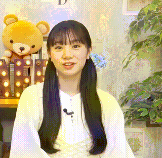 a young girl with pigtails is sitting in front of a teddy bear and a sign .