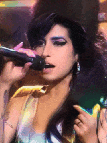 a woman is singing into a microphone with a ring on her finger