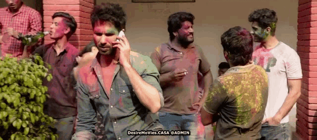 a man is talking on a cell phone while others are covered in powder