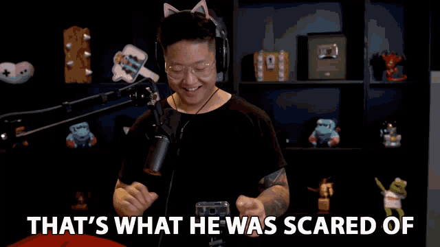 a man wearing headphones and glasses is standing in front of a microphone with the words that 's what he was scared of