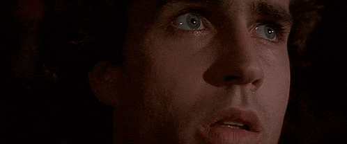 a close up of a man 's face with blue eyes looking up at something .