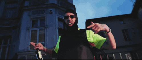 a man wearing a black mask and sunglasses holds a bottle