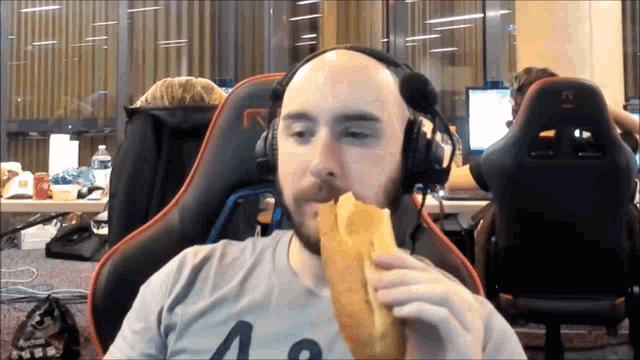 a bald man wearing headphones eating a sandwich